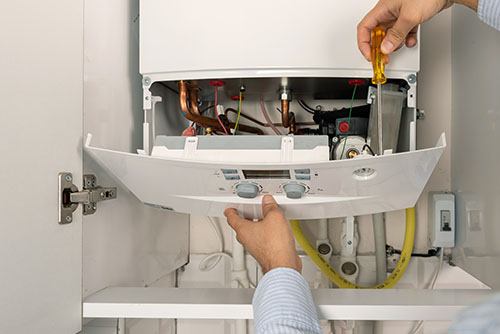 Heating technician repairing a residential boiler in Long Beach