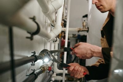 Technician inspecting commercial plumbing pipes in Long Beach