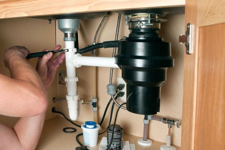Plumber repairing a garbage disposal in Long Beach